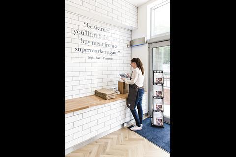 Store worker checking iPad at checkout of Farmison & Co butcher